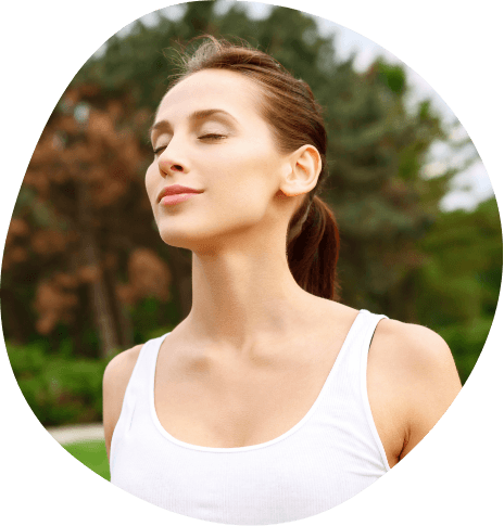 Woman in white tank top smiling peacefully outdoors