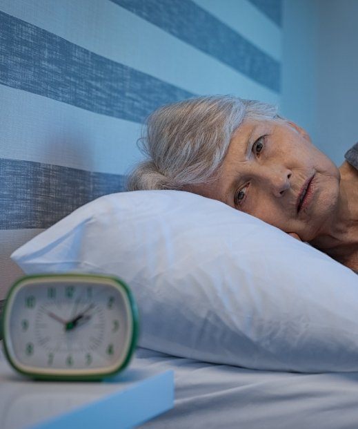 Senior woman lying awake at night needing insomnia treatment in Irving