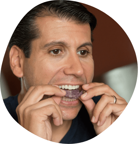 Man placing a light purple oral appliance in his mouth