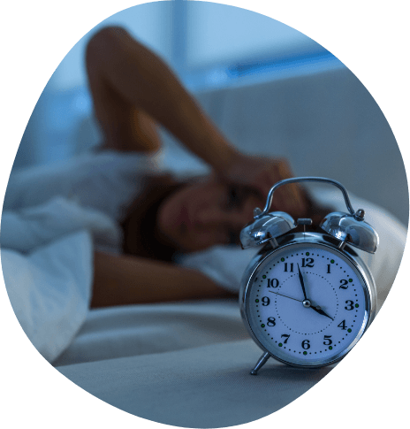 Woman lying awake in bed next to alarm clock showing 4 A M