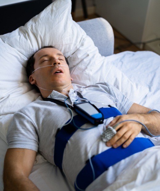 Sleeping man hooked up to cords for sleep testing in Irving