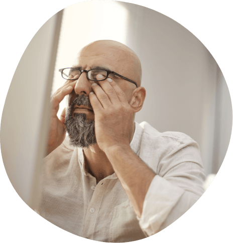 Frustrated man with beard and glasses rubbing his eyes