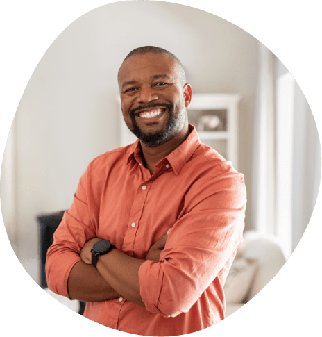 Smiling man in orange shirt standing with arms crossed