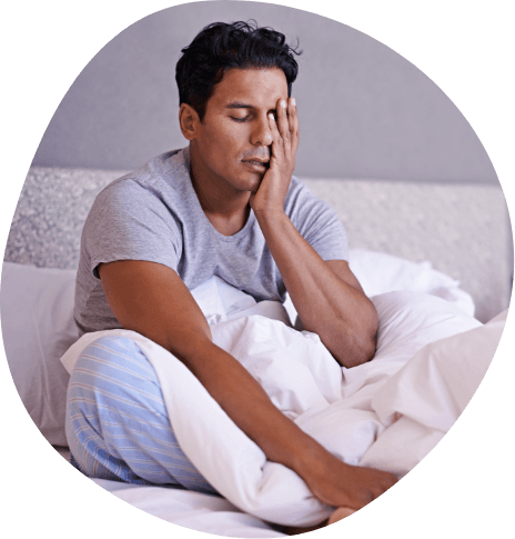 Frustrated man sitting on bed and resting his head in his hand