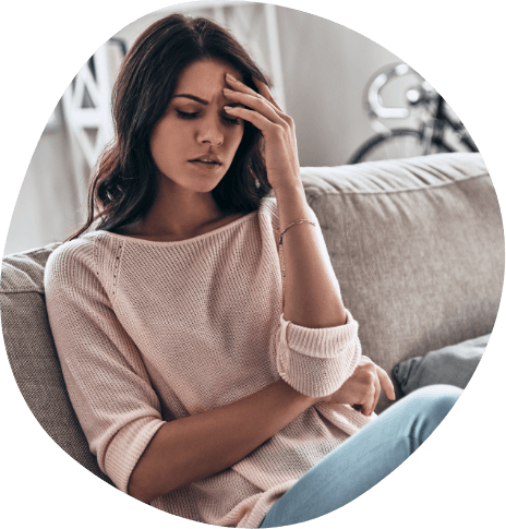 Frustrated woman sitting on couch and resting her head in her hand