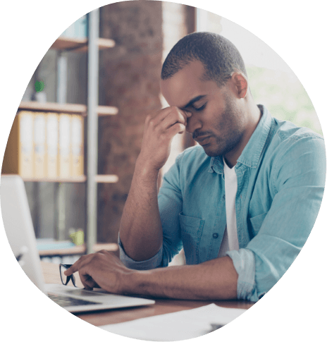 Man sitting at computer pinching bridge of nose in frustration