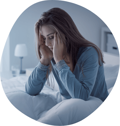 Woman sitting awake in bed and touching her temples in frustration