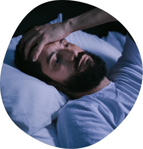 Man lying awake in bed touching his forehead