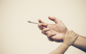 a child pushing away a hand holding a cigarette