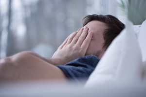 a man covering his face while trying to sleep