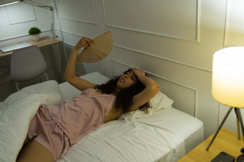 woman feeling hot while in bed